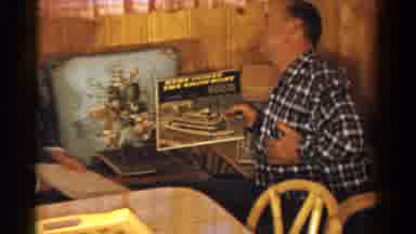 Ontario Canada (1958): Two Men Sit Conversing While One Shows Record Album With