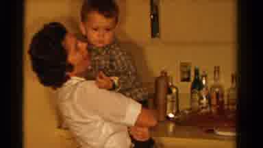 Ontario Canada (1958): Woman Wearing White Shirt Holds Boy In Arms By Kitchen