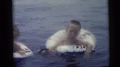 CAMDEN NEW JERSEY USA-1959: Two Kids Play In The Water With Floats While The Baby Sleeps