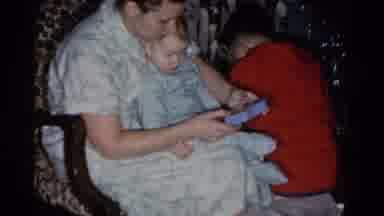 Catskill New York USA (1959): Woman Holds Baby Wearing Green Pajamas While Tapping