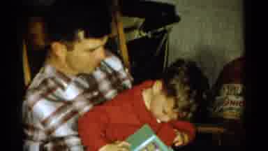 Catskill New York USA (1959): Man Sitting On Chair Holds Boy Looking At Toy Girl