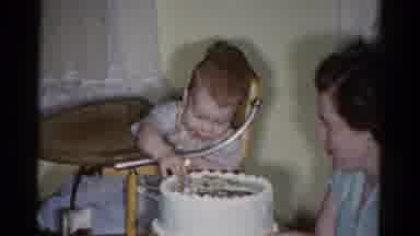 Catskill New York USA (1959): Cute Smiling Baby Touching Birthday Cake With