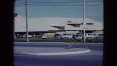 Nevada USA (1959): Panning Shot Of Cars Driving In Front Of A Car Park Followed By