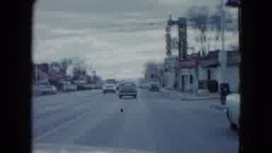 Nevada USA (1959): Cars Are Fast On The Road With Turning And Many Buildings Near