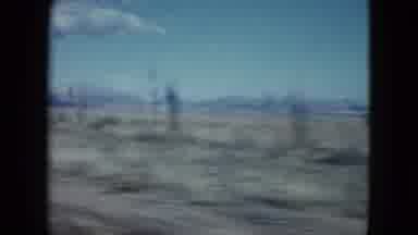 Nevada USA (1959): Driving Along A Desert Landscape With Blue Skies And Hills In