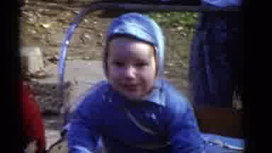 Camden New Jersey (1960): Baby Wearing Blue Coat Smiles At Cameraman On Sunny Day