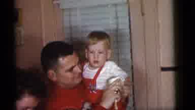 Camden New Jersey (1960): Man Wearing Red Sweater Holds And Wipes Hand Of Baby