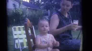Camden New Jersey (1960): Baby Wearing Pink Sunsuit Sits In Brown Chair On A Clear