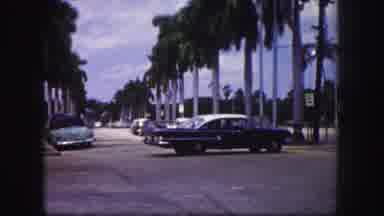Tampa Florida USA (1960): Nice Blue Car Making A Left Turn Onto A Busy Palm Tree