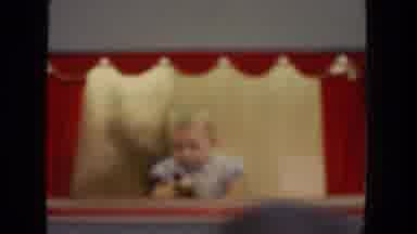 San Diego California (1962): Baby Wearing Blue Shirt Plays With Hand Puppet On Red
