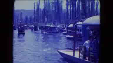 Mexico City (1962): Two People Paddle A Boat Through Other Boats On A Busy River