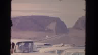 Los Angeles California USA (1962): Line Of Cars Driving Down Desert Road On A
