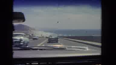 Los Angeles California USA (1962): A Classic Car Is Driving Down The Road Next To
