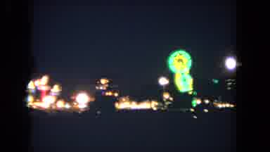 LOS ANGELES CALIFORNIA USA-1962: Blurry Pan Of A Carnival At Night With Spinning Neon Ride