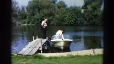 Illinois USA (1962): Man Starts Motor On A Boat Parked Near A Small Dock While One
