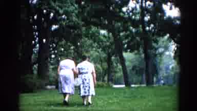 Illinois USA (1962): Woman Wearing Red Dress Walks Toward White Building On A