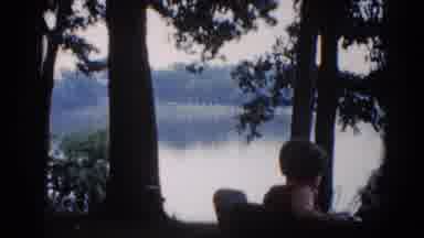 Illinois USA (1962): Woman Sits On Bench Looking At Lake On A Clear Day