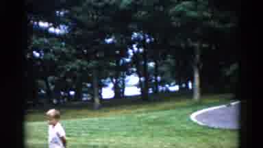 Illinois USA (1962): A Boy Walks In The Grass Next To A House With A Circular