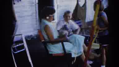 Illinois USA (1962): Woman Holding A Puppy While Children Pet It Cuts To Two Men
