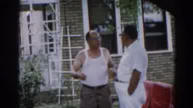 Illinois USA (1962): Two Men Standing Outside Of Brick Home Having A Conversation