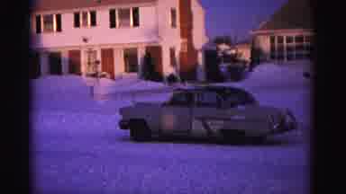 Hagerstown Maryland USA (1962): Old Tan Car Leaving Suburb During Snowy Afternoon