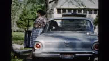 Wauconda Illinois USA (1961): Woman Stands Next To Blue Car While Man Wearing