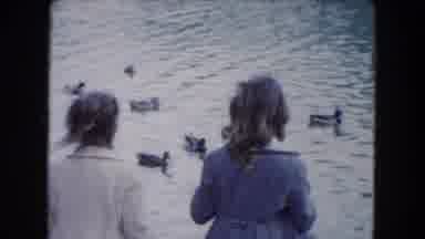 South Carolina USA (1961): Two Girls Throw Food At Ducks In Water
