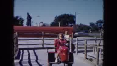 South Carolina USA (1961): Young Girls Riding Play Tractors Through A Fenced Area