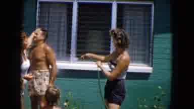 South Carolina USA (1961): A Woman In A Swimsuit Rinses Off A Man And Little