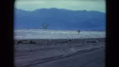 Nevada USA (1961): Car Driving Down The Road And Passing Another Car In A Desolate