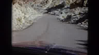 Nevada USA (1961): A Vehicle Takes A Turn Around A Corner Of Narrow Road With