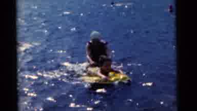 CAMDEN NEW JERSEY USA-1961: Mother Helps Child Onto A Raft To Practice Swimming