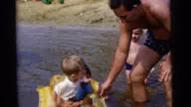 Camden New Jersey USA (1961): A Man Helps A Child Float On A Water Toy Another