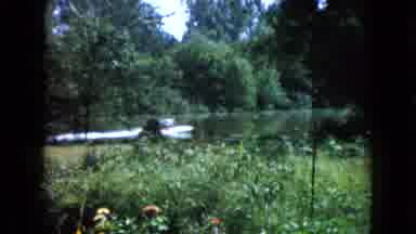 Wauconda Illinois USA (1960): Older Woman In Garden Cutting Away To A Motor Boat