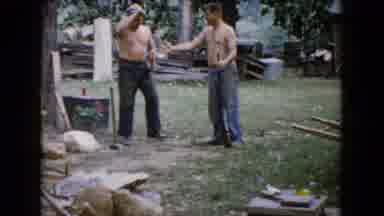 Wauconda Illinois USA (1960): Two Shirtless Men Trade A Sledge Hammer For A Rifle
