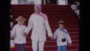 Buffalo New York USA (1961): Woman Wearing White Coat Walks Down Red Staircase On