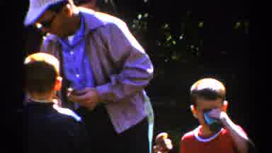 Catskill New York US-1962: Man Helps Child With Drink At Outdoor Family Gathering