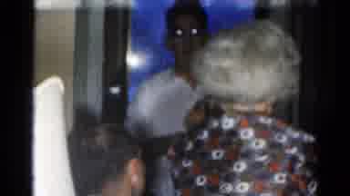 Catskill New York US (1962): A Child Sitting On The Floor And Adults Coming Inside