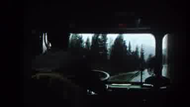 Summit County Colorado USA (1962): Man Driving Tour Bus Past Green Trees On A