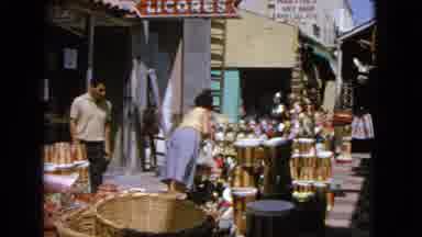 Barrington Illinois USA (1963): Outdoor Market With Woman Examining A Toy Doll As