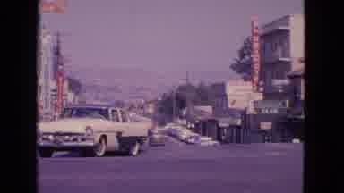 Barrington Illinois USA (1963): Two Men Cross A Busy City Street While A Car Turns