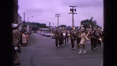 Barrington Illinois USA (1963): A Marching Band Marches Through A Small Town; The