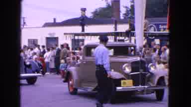 Barrington Illinois USA-1963: People Are Standing Beside The Road To Watch A Classic Car Parade