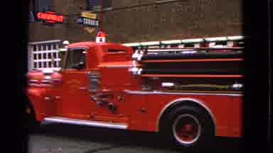 Barrington Illinois USA (1963): Red Fire Truck Slowly Going Down A Street With Its