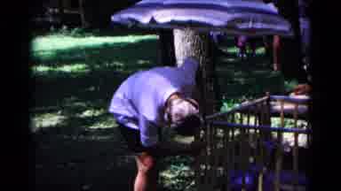 Cold Springs New York USA (1963): Man Fiddles With Playpen Side At An Outdoor