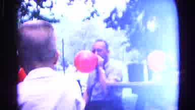 Cold Springs New York USA (1963): Man Wearing Blue Shirt Blows Up Red Balloon On A