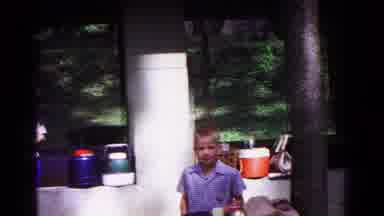 Cold Springs New York USA (1963): Boy Wearing Blue Shirt Stands Next Vendor Booth