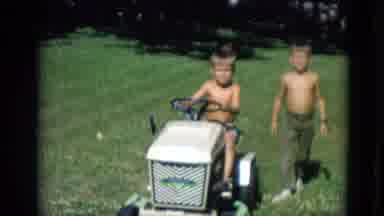 Lincoln Nebraska (1963): One Child Drives A Motorized Lawn Mower With Another