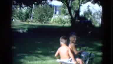 Lincoln Nebraska (1963): Two Children Ride On Small Motorized Lawn Mower Outside