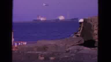 San Francisco California-1963: Man Fishing On Pier With Cargo Ships In Background